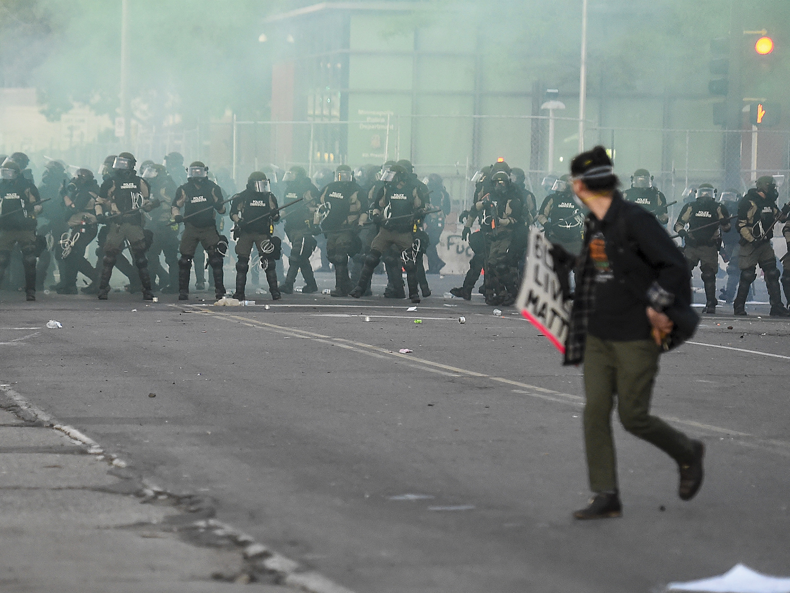 A man walking away from a line of police in riot gear