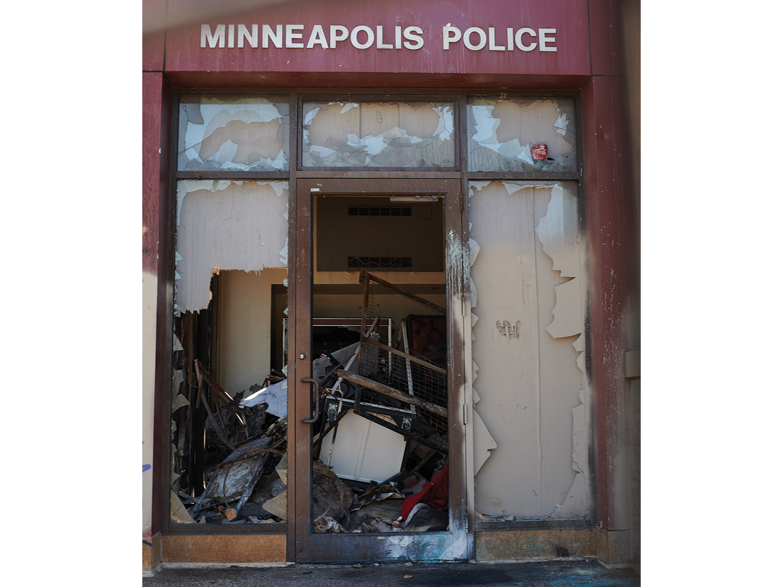 Entrance of a Minneapolis Police Station with the windows broken and rubble in the entryway