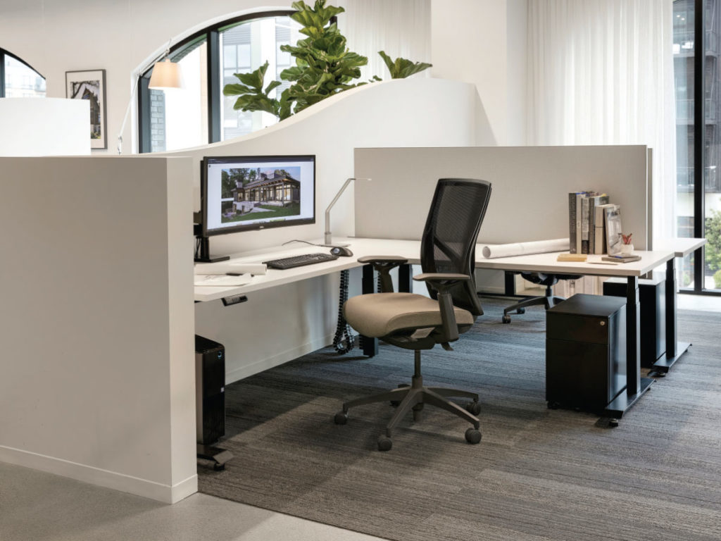 Workstation pods are separated by Sheetrock walls that start low and curve up against the glass wall for more privacy. The floor-to-ceiling fabric helps the acoustics and softens the space. 