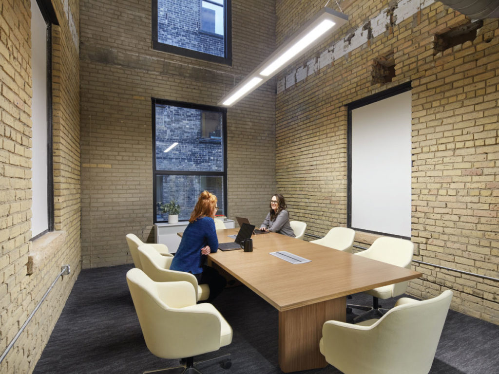 An exterior wall connects two separate buildings, creating a two-story boardroom that echoes the alleys found in the neighborhood.