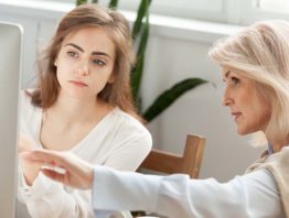 An older woman works with a younger woman at a computer