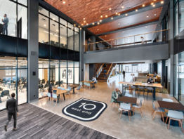 The two-story lobby features an upper walkway lined by cable railings. The big windows and the workspaces dotted throughout enhance the lobby’s community feel and help bring tenants together.