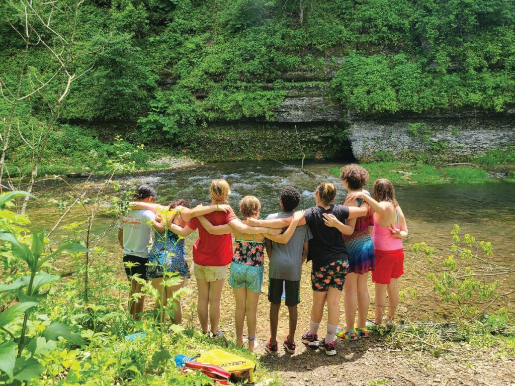 group of kids gather around a river