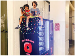 Two children sitting on top of The Donut Trap vending machine