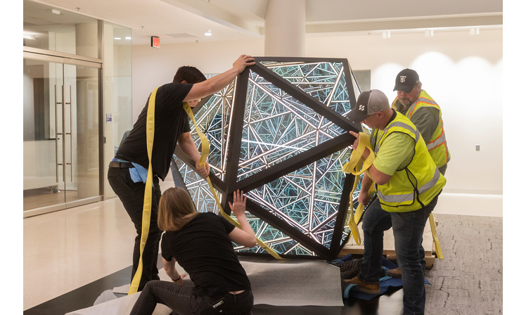 Workers installing an art piece at the Schoenecker Center