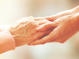 Younger hands holding elder hands, illustrating concept of family caregiving